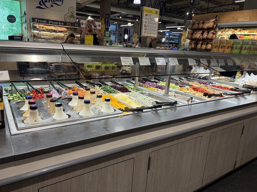 アメリカのスーパーの惣菜ショーケース。壁沿いに長く伸びた売り場に多種類の料理が並ぶ
