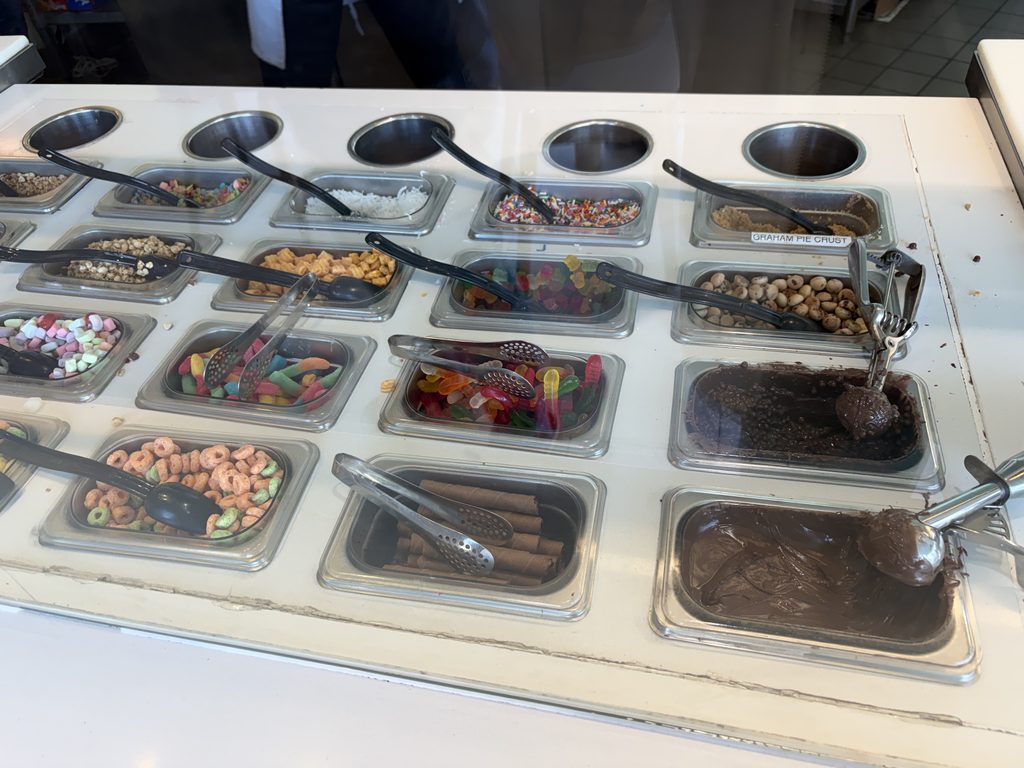 Pinkberryのトッピングバー。金属のバットにチョコレートやナッツ、キャンディなどが並んでいる