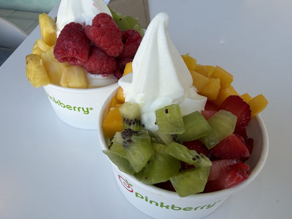 Pinkberryのカップに盛られたヨーグルトアイス2つ。ラズベリーやマンゴー、キウイ、イチゴなど生の果物がトッピングされている