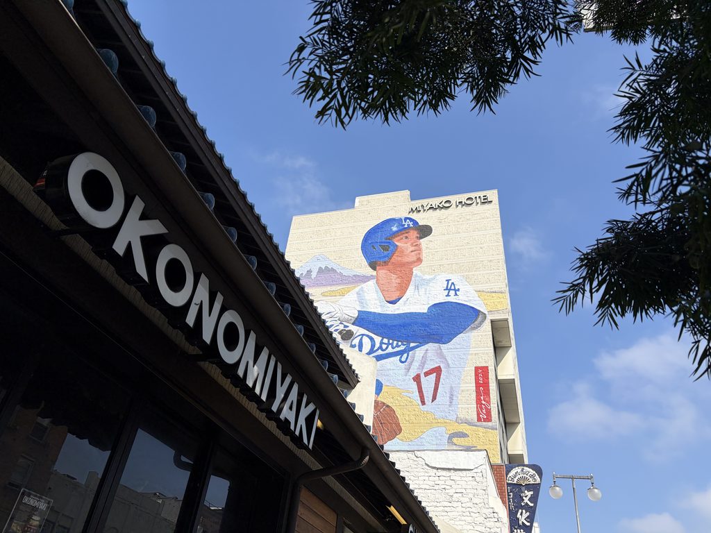 都ホテルの壁に描かれた大谷翔平の壁画と、手前のお好み焼き店の看板